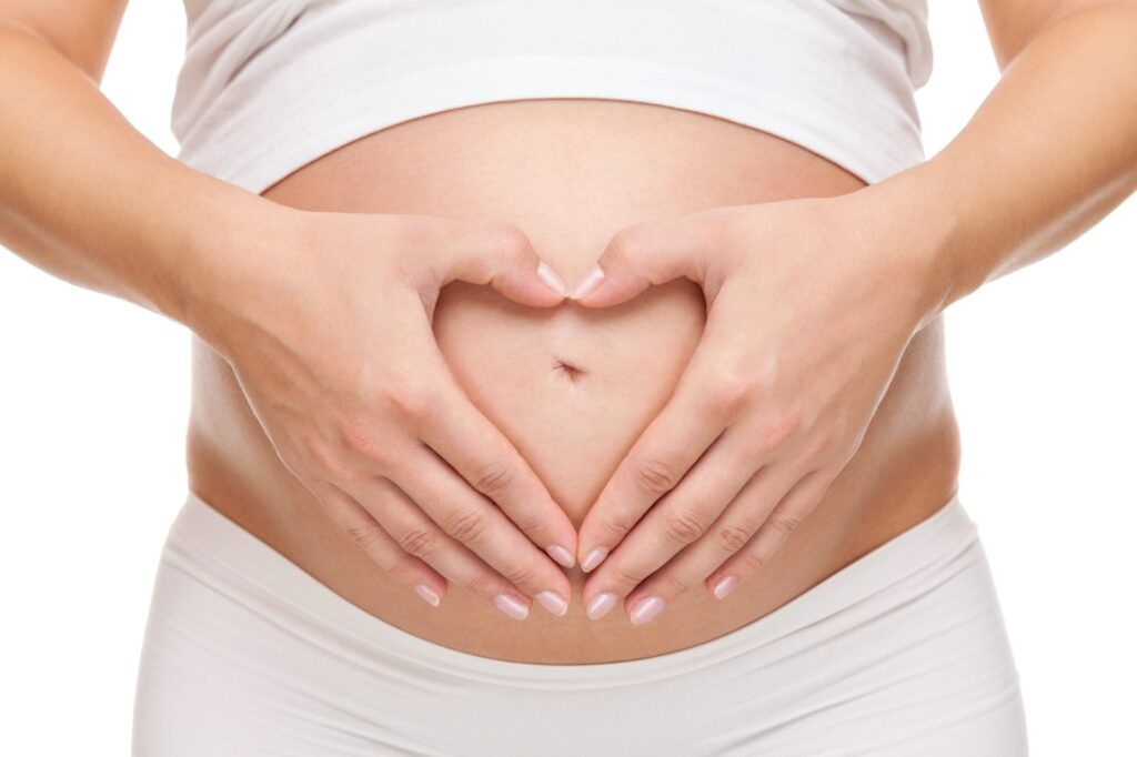 Mujer embarazada formando un corazón con las manos sobre la barriga
